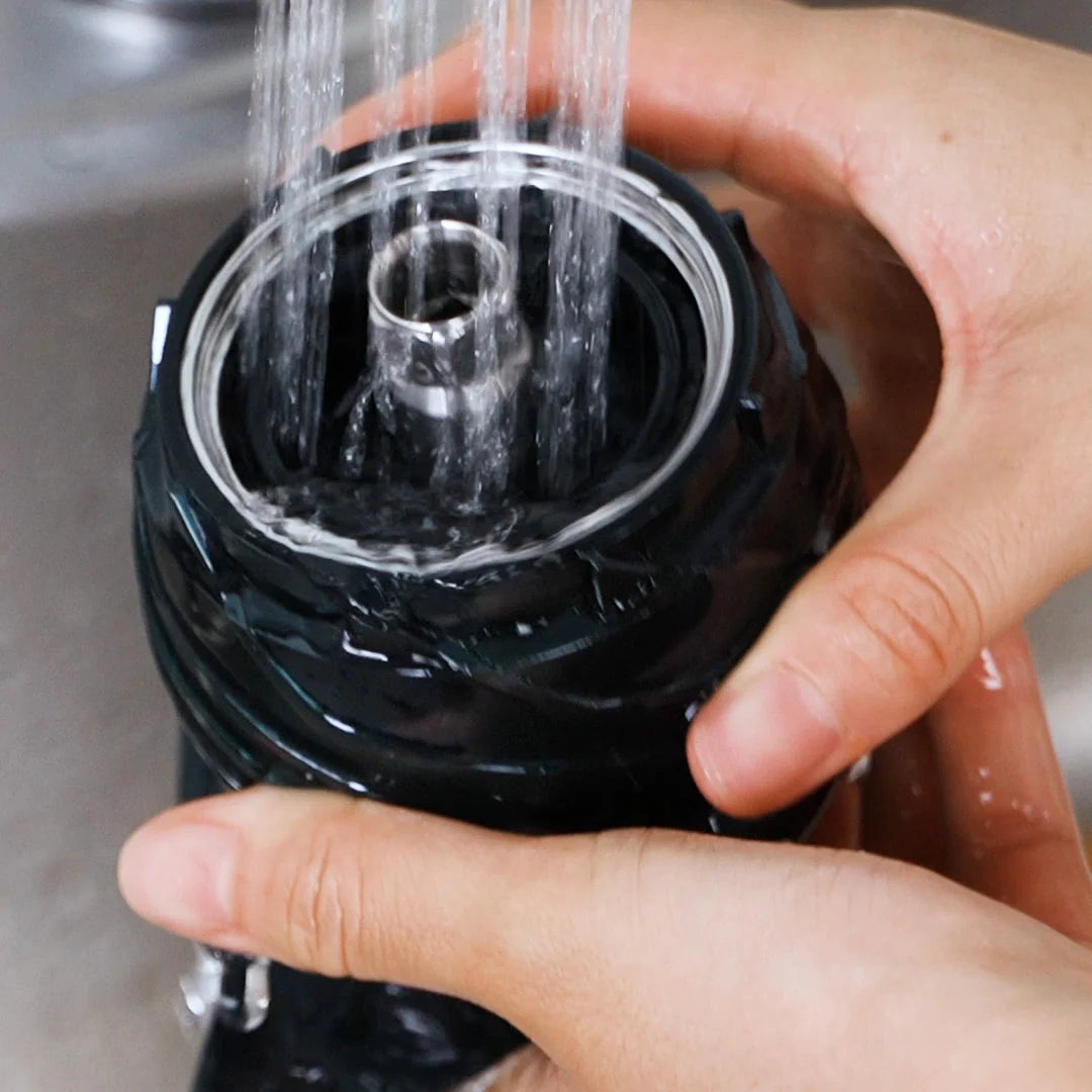 Kuvings AUTO10S slow juicer juicing screw being rinsed under running water for quick and easy cleaning.