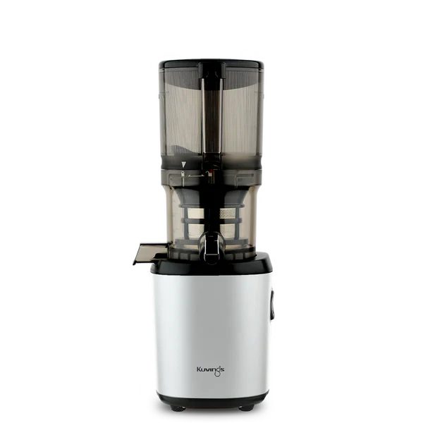 Straight-on studio product shot of a silver Kuvings AUTO6 whole slow juicer with its large transparent grey mega-hopper bowl assembly attached, isolated against a transparent grid background.