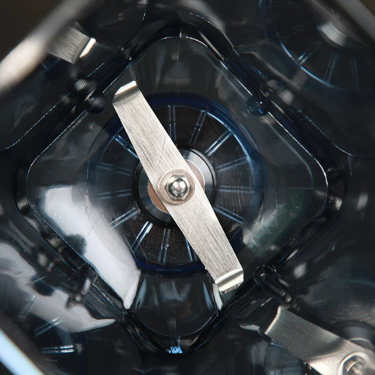 Top-down close-up view looking into the bottom of a Kuvings CB1000 blending jar, showcasing the sharp stainless steel blade assembly.