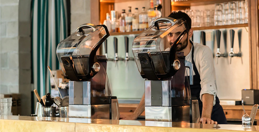 Kuvings CB1000 commercial blenders on a bar counter with a barista in a professional café setting.