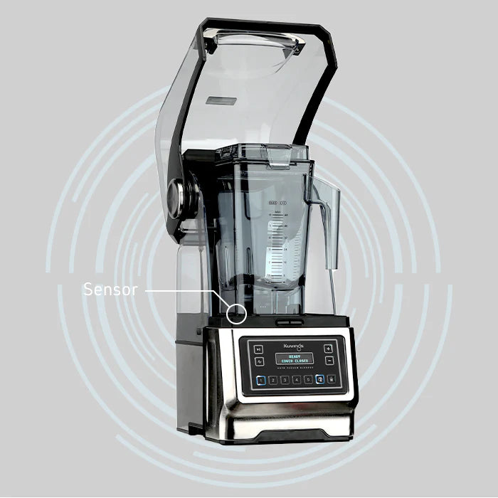 Angled front view of a Kuvings CB1000 professional vacuum blender with its clear sound cover open, featuring a graphic label pointing to the built-in safety sensor against a gray background with concentric circles.