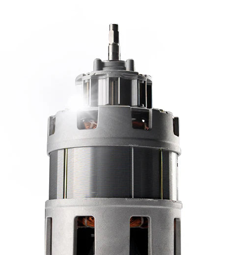 Straight-on, close-up studio product shot of the heavy-duty electric induction motor component from a Kuvings Chef CS700 commercial slow juicer, showing its metallic housing, drive shaft, and internal copper wiring with a bright lens flare highlight against a clean white background.