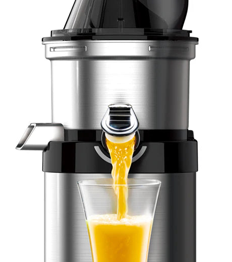 Straight-on close-up studio shot of the upper drum section of a brushed stainless steel Kuvings Chef CS700 commercial slow juicer with its chrome smart cap open, pouring fresh orange juice into a glass against a white background.