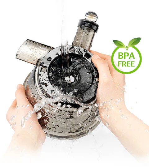 High-angle close-up studio shot of a pair of hands rinsing a dark-tinted clear Tritan juicing bowl component from a Kuvings slow juicer under a stream of running water, accompanied by a green 'BPA FREE' leaf badge graphic on a white background.