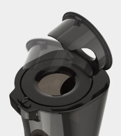 High-angle studio product shot of the dark translucent feeding chute component of a Kuvings EVO820 whole slow juicer, showcasing the open mechanism of its circular black plastic flip-gate lid on a light grey background.