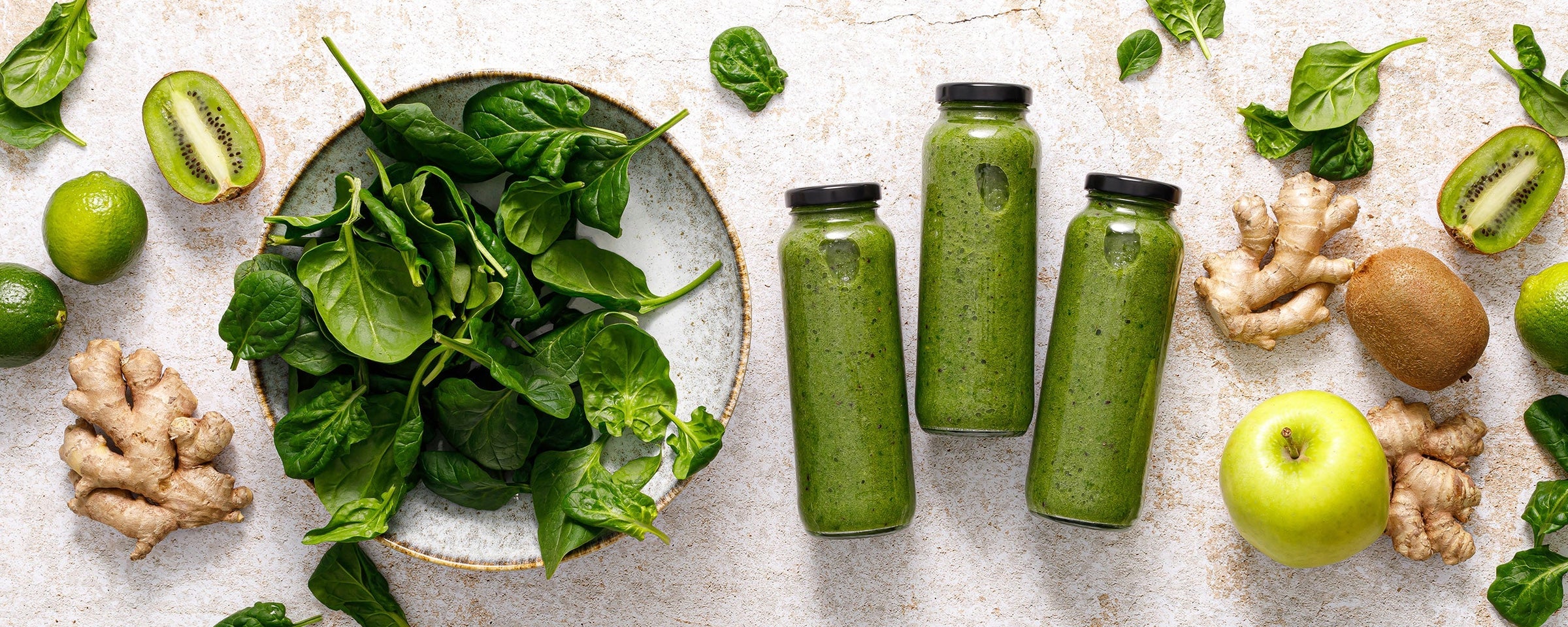 Kuvings green smoothie bottles with kiwi, spinach and ginger, highlighting fresh ingredients for healthy homemade juice and smoothies.
