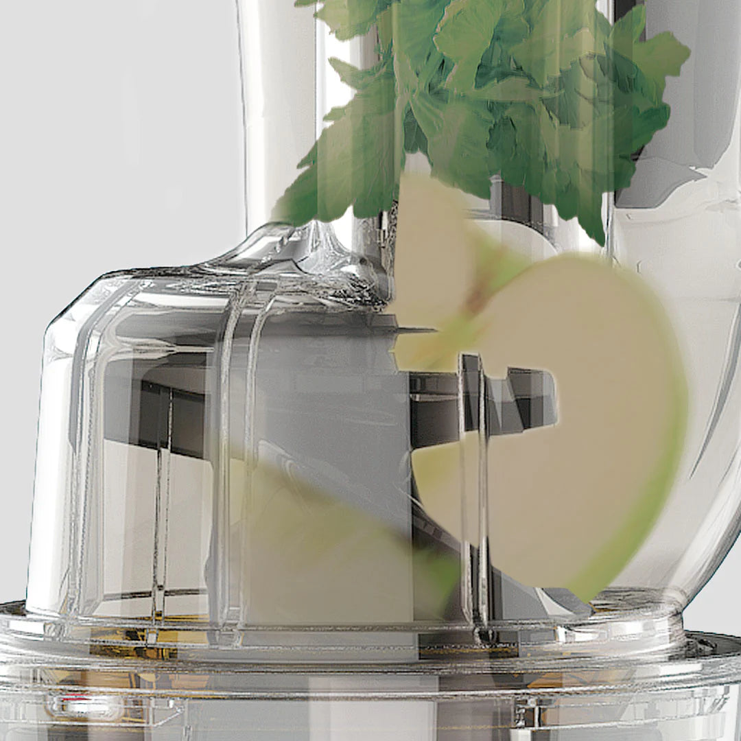 Close-up conceptual studio shot of the clear Kuvings REVO830 feeding chute, showing the integrated auto-cutting mechanism chopping an apple slice and celery stalk on a light grey background.