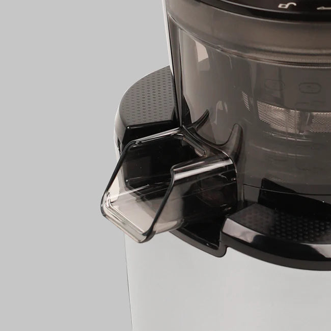 Close-up studio product shot focusing on the transparent dark grey pulp extraction outlet chute on the juicing bowl of a Kuvings REVO830 whole slow juicer against a grey background.